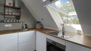Una cocina moderna con tragaluz, armarios blancos y encimera de madera.