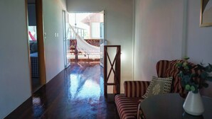A hallway with a hammock, a striped sofa, and a plant.