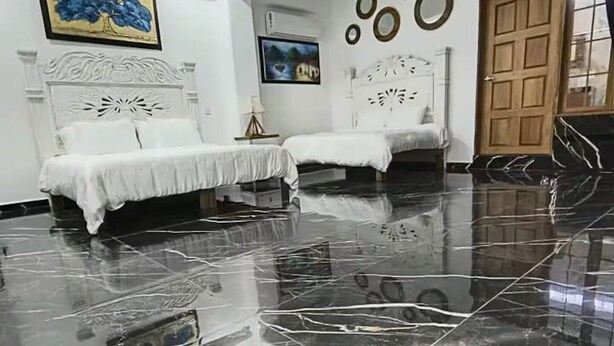 A hotel room with two beds, a marble floor, and a wooden door.