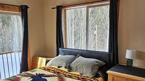 A bedroom with a bed, a nightstand, a ceiling fan, and a window with curtains. - High-alpine private retreat 2-bedroom house in cozy Alma, close to Breckenridge (Alma)