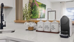 A kitchen with a coffee maker, sugar and coffee containers, and a plant. - Kick back and relax in this calm, stylish home! Close to downtown, beaches, park (St. Petersburg)