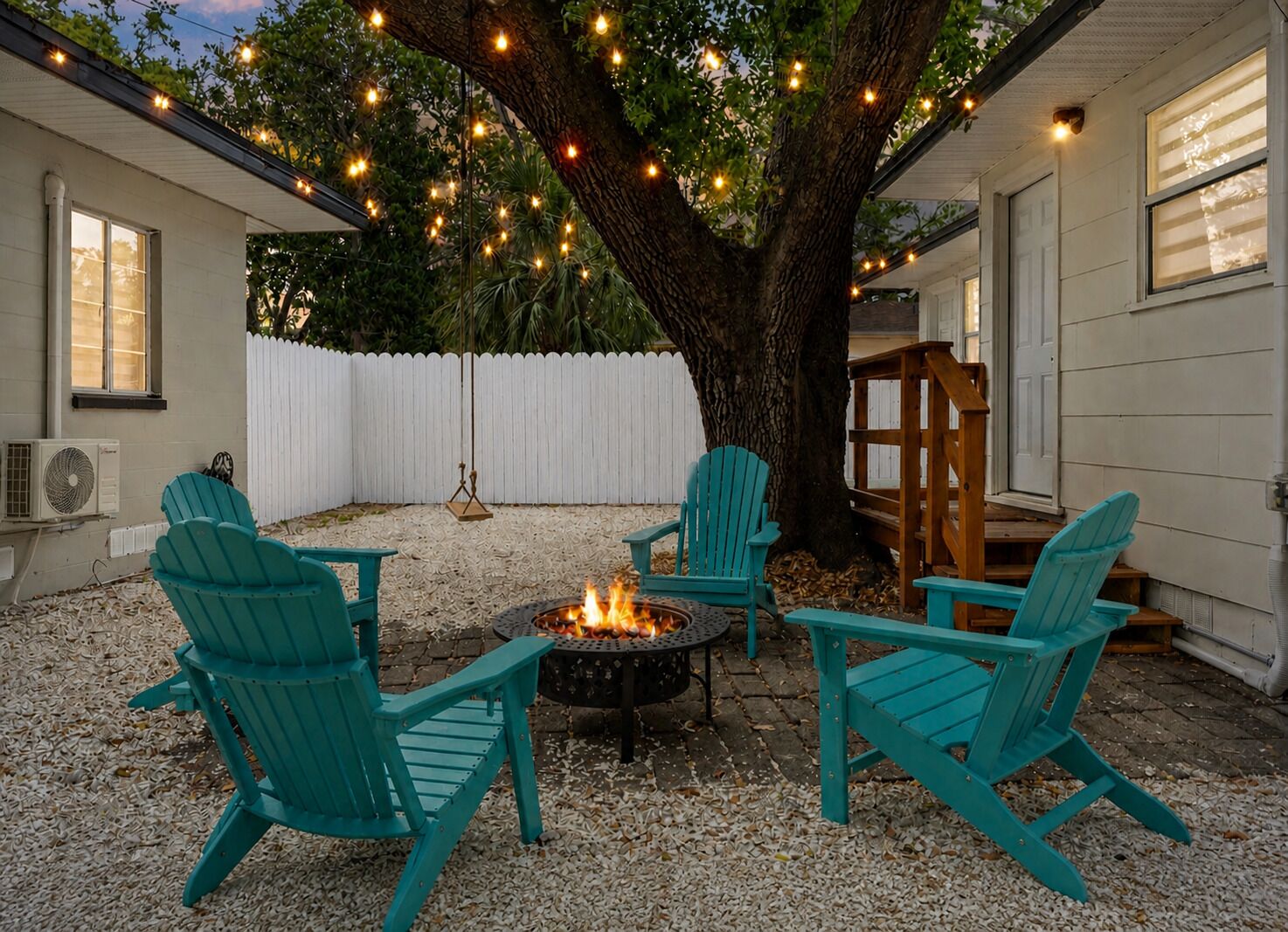 Un cortile con un braciere, posti a sedere all'aperto e luci decorative appese.