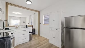 A modern kitchen with white cabinetry, a stainless steel refrigerator, and a large mirror. - Kick back and relax in this calm, stylish home! Close to downtown, beaches, park (St. Petersburg)