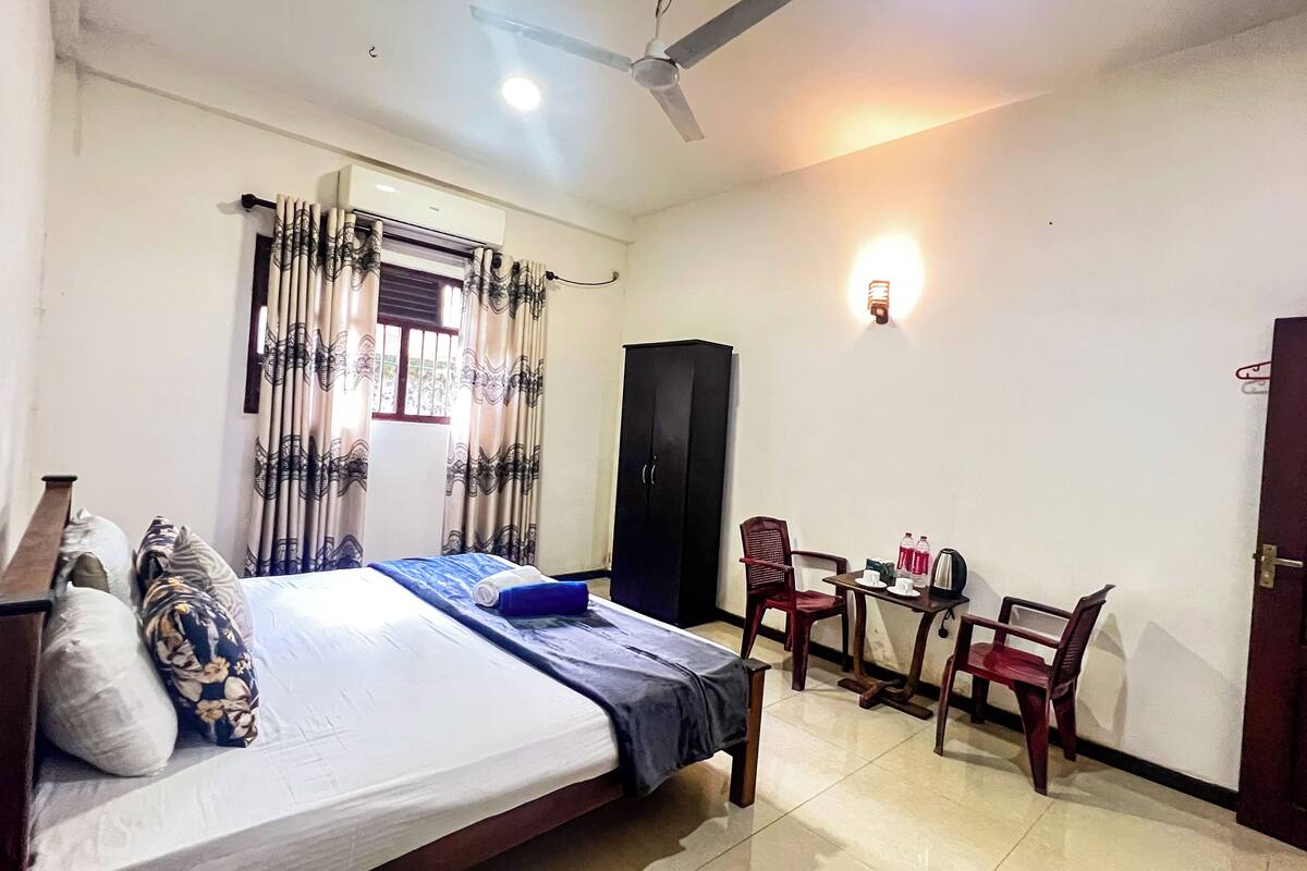 Une chambre à coucher comprenant un lit, une armoire, un bureau avec des chaises et une porte.