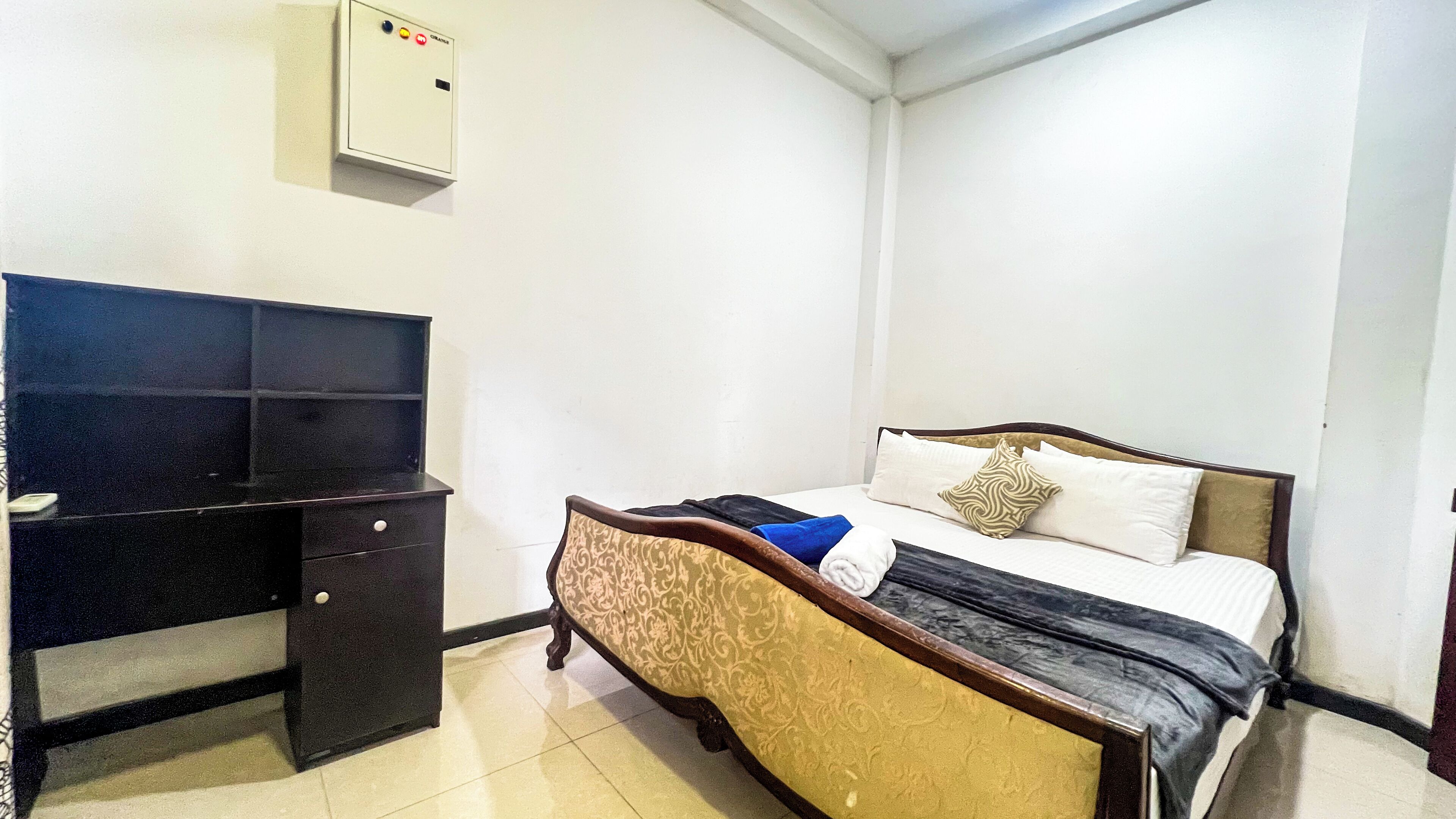 Une chambre à coucher comprenant un lit, un bureau et un panneau de commande fixé au mur.