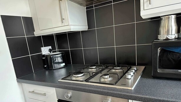 Una cocina con estufa a gas, horno y cafetera sobre el mostrador.