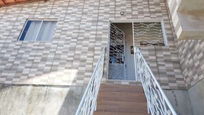 Un edificio con fachada de baldosas a cuadros, una reja en la entrada y un ventanal pequeño.