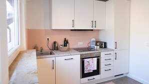 Una cocina moderna con armarios blancos, un horno de acero inoxidable y una encimera con hervidor y cafetera.