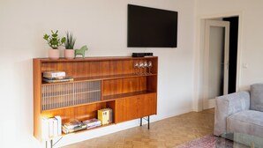 Una sala de estar moderna con un mueble bajo para equipo audiovisual, un televisor de pantalla plana y una mesa de centro de vidrio.