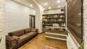 A modern living area with a brown sofa, white brick walls, and a wooden floor. - Salam Old Baku Hostel (Baku)