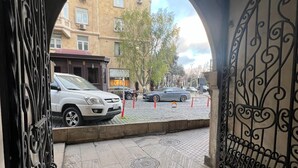 An arched doorway leading to a street with parked cars and buildings in the background. - Salam Old Baku Hostel (Baku)
