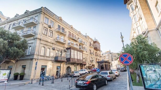 A street view with historic buildings, a no parking sign, and parked cars. - Salam Old Baku Hostel (Baku)