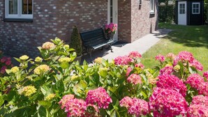 A brick house with a porch, a bench, and a small shed in the background. - Luxurious Coastal Villa Near Forest (Sint Maartensvlotbrug)