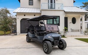 A golf cart parked in front of a modern house with a garage, a balcony, and a well-maintained lawn. - Upscale Seagrove Home + Private Pool & Golf Cart (Santa Rosa Beach)
