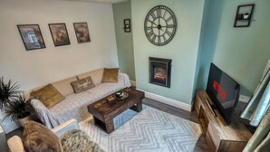 A living room with a sofa, a coffee table, a TV, and a fireplace. - Cosy 2BDR Trafford Cottage, Fits 5, EV charger, WIFI, Parking 
 (Partington)