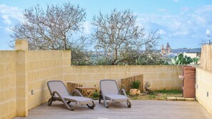 Zona de piscina amb dues gandules i una taula petita, envoltada per un mur baix i cactus.