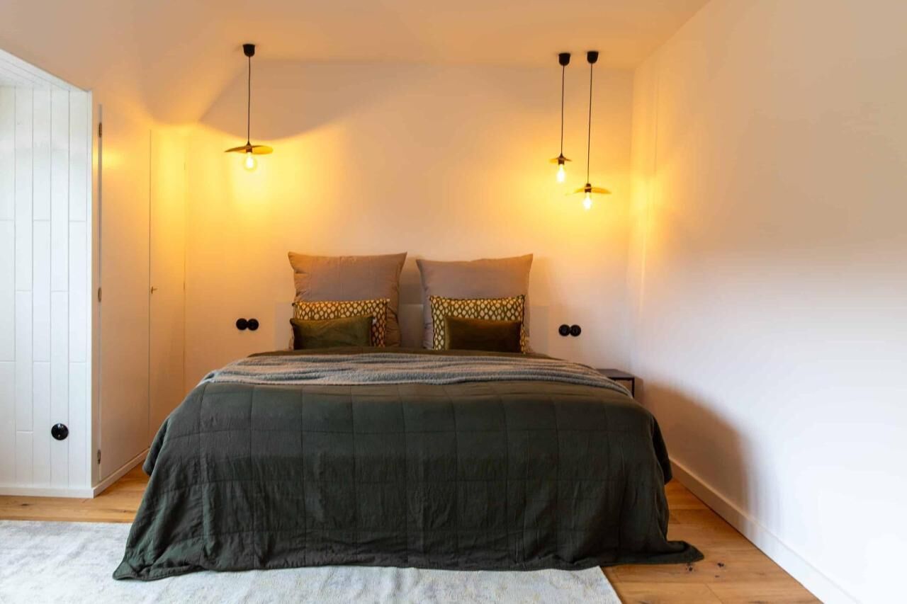 A bedroom with a bed, two bedside tables, and a door.