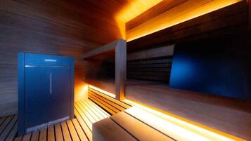 A modern sauna with wooden walls and benches, a Harvia sauna heater, and a wooden floor.