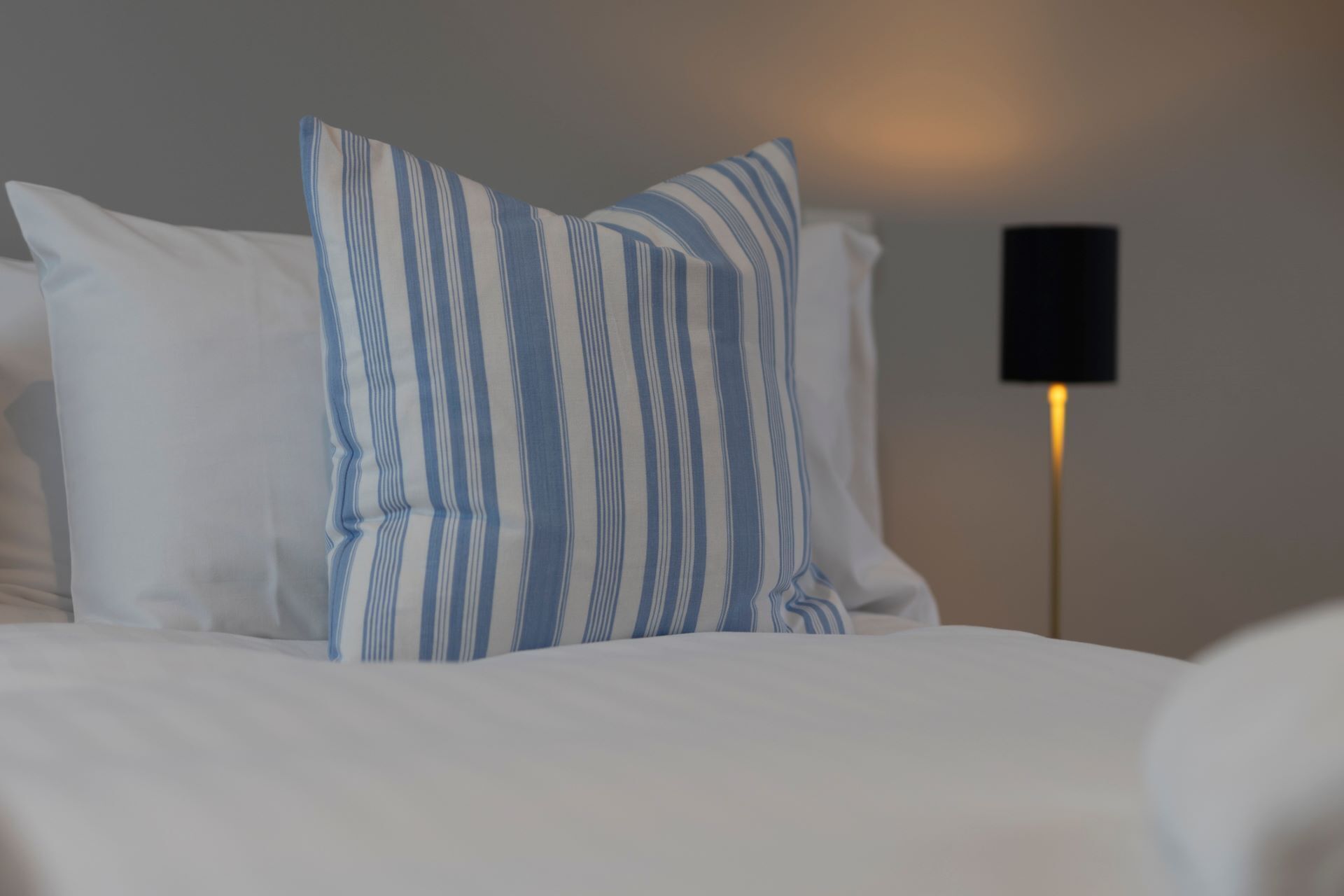 Ein Bett mit weißer Bettwäsche und zwei gestreiften Kissen.