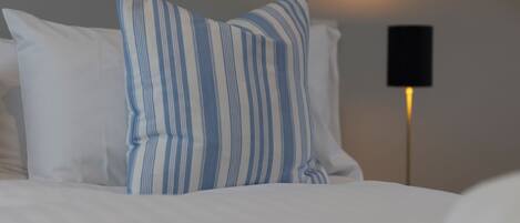 Ein Bett mit weißer Bettwäsche und zwei gestreiften Kissen.