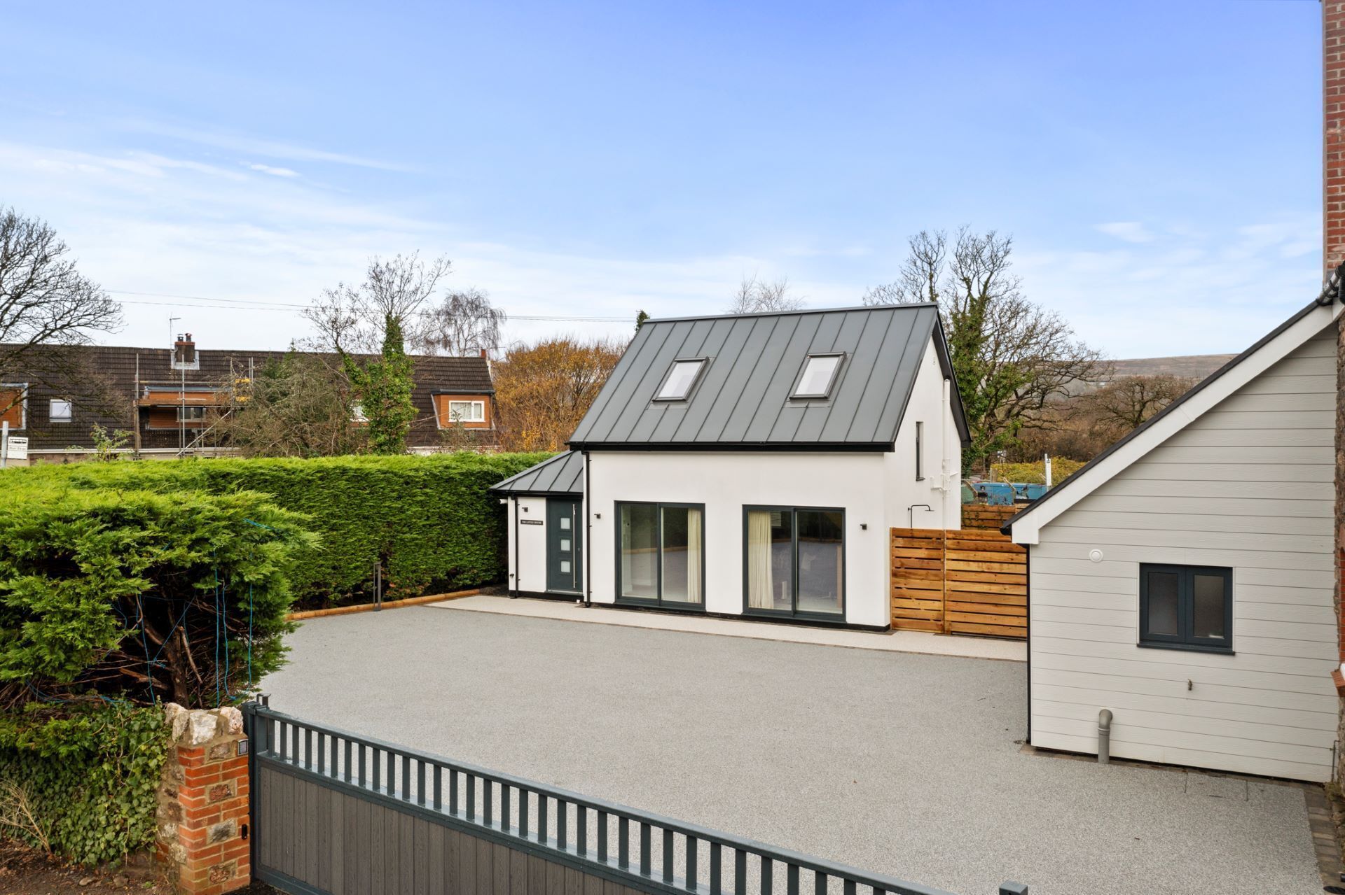 A modern two-story house with a sloped roof, large windows, and a paved driveway.