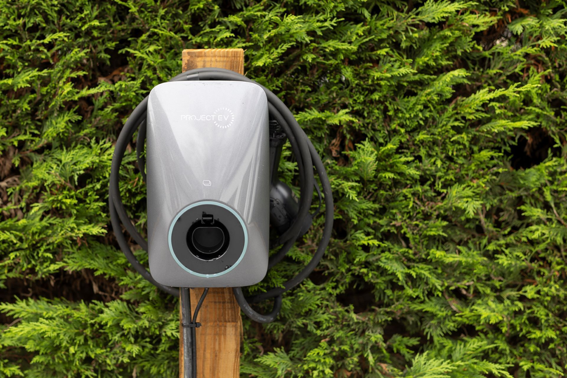 Un panneau solaire portant l’inscription « PROJECT EV » est fixé sur un poteau en bois.