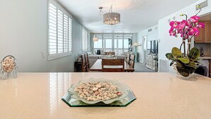 A spacious kitchen with a dining area, large windows, and a chandelier.