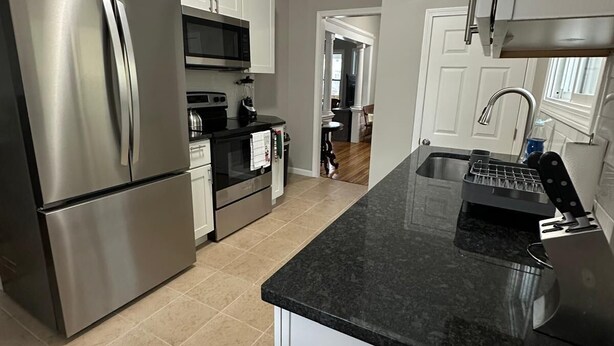 A modern kitchen with stainless steel appliances, a granite countertop, and a view into the dining area. - Cozy Home in Holyoke with 3 bedrooms (Holyoke)