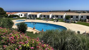 Een resort met een zwembad, ligbedden en uitzicht op zee.