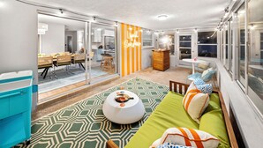 Una sala de estar acogedora con un sofá verde, una mesa de centro redonda y un separador a rayas.