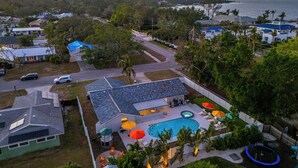 Zona residencial con piscina, mobiliario exterior y vista al océano al atardecer.
