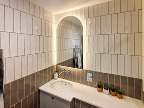 Een moderne badkamer met een grote spiegel, een wastafel en een handdoekhouder.