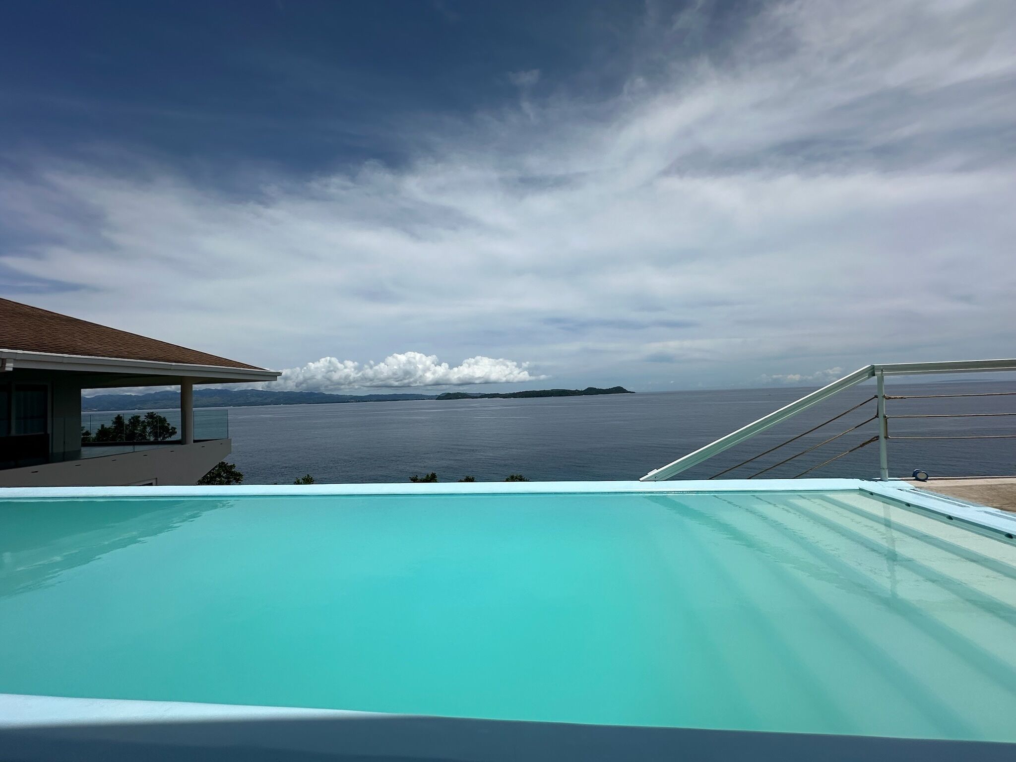 A modern pool with a clear view of the sea and distant islands.