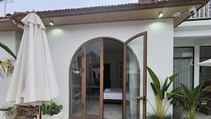 A residential property with a glass door entrance, a white umbrella, and potted plants. - Vu's Homestay Tam Coc (Nam Hoa Lu)