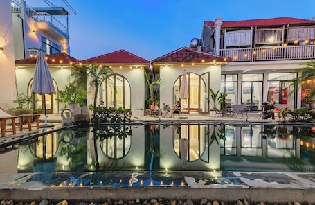 Una piscina al aire libre, sombrillas, sillones reclinables de piscina