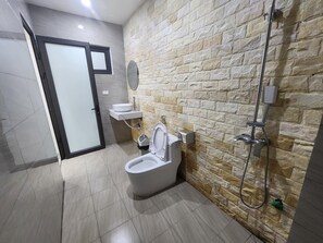 Et moderne badeværelse med stenvæg, toilet, vask og brusebad.