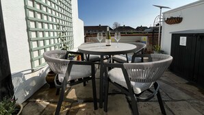A patio with a round table and four wicker chairs, a green lattice fence, and a black gate. - PEACEFUL, CENTRAL LUXURY COTTAGE WITH PARKING,WATERSIDE TERRACE (Arundel)