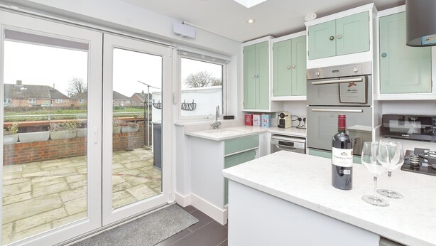 A modern kitchen with a large island, a built-in oven, and a wine bottle. - PEACEFUL, CENTRAL LUXURY COTTAGE WITH PARKING,WATERSIDE TERRACE (Arundel)