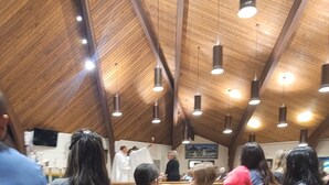 Interior de iglesia con bancos de madera y un techo alto e inclinado.