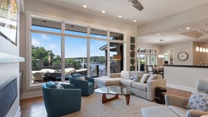 A spacious living room with a large window, a glass coffee table, and a sofa. - Luxury Lakefront Home with Heated Pool and Protected Cove (Sunrise Beach)