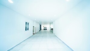 A bright, white hallway with a car parked at the end. - beestay Hotels Tirupati (Tirupati)