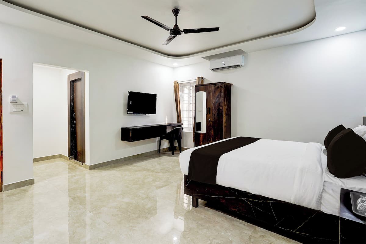 Une chambre d’hôtel moderne équipée d’un lit, d’un bureau, d’une télévision et d’une armoire.