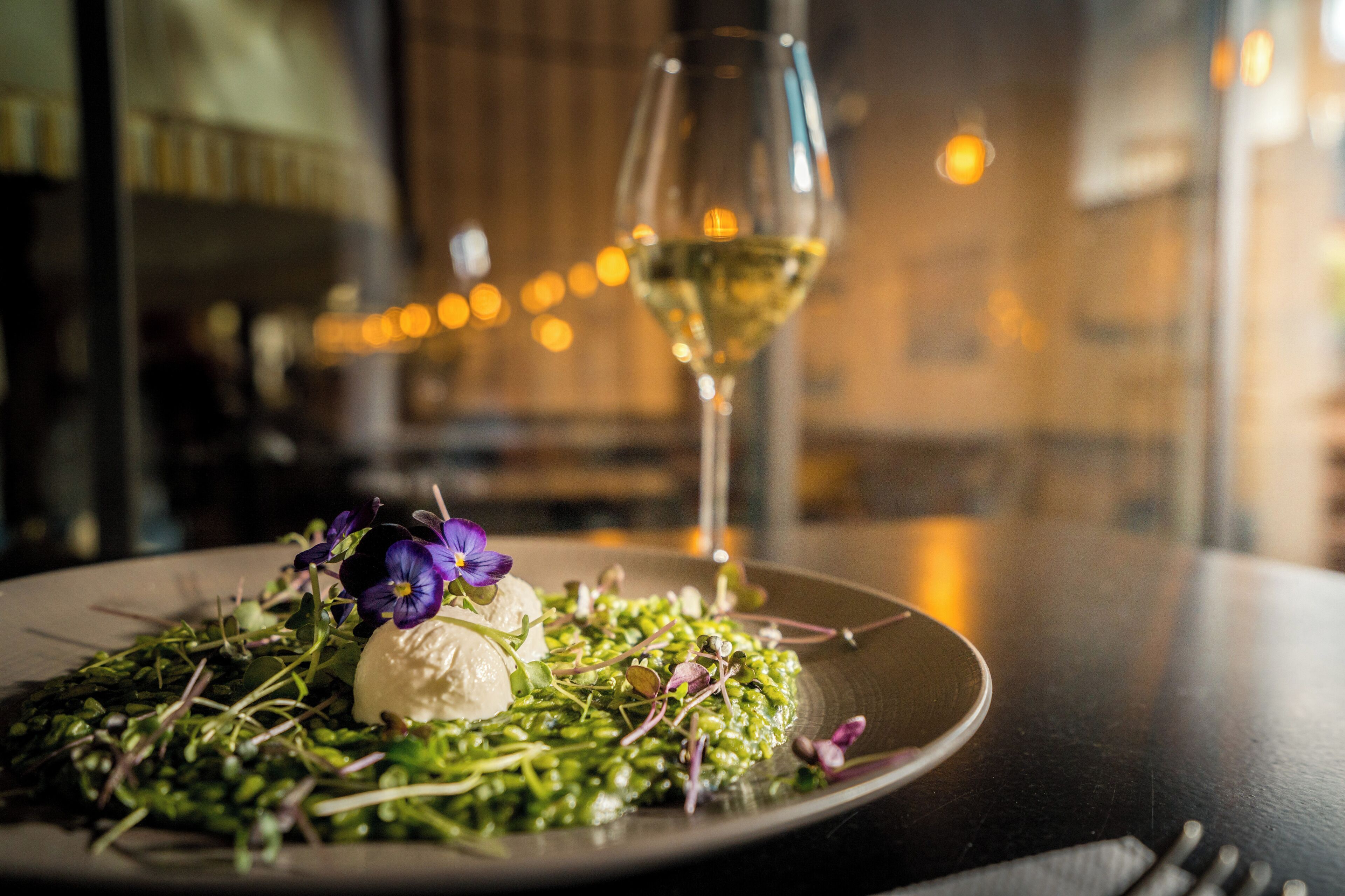 A plate of food with a glass of white wine on a table.