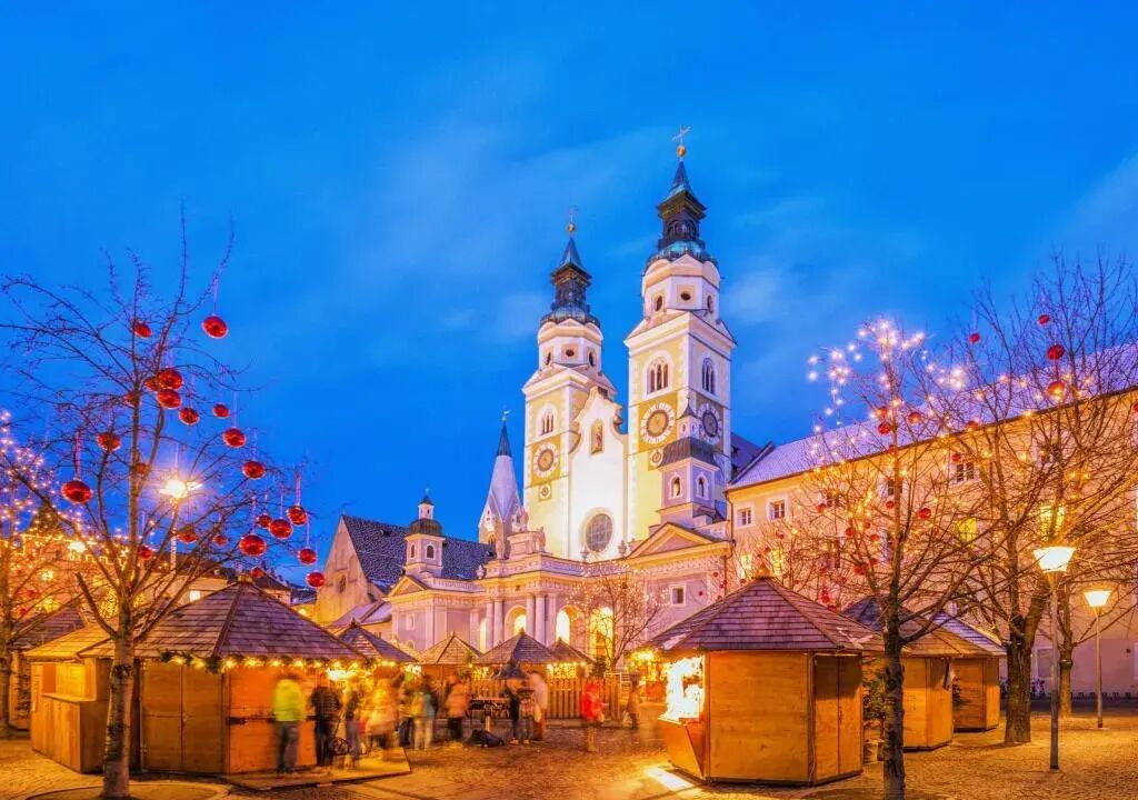 Ein historisches Gebäude mit zwei markanten Türmen und einem Innenhof mit Marktständen.