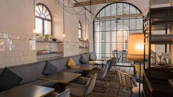 Un restaurante con una barra alargada, asientos acolchados y ventanas amplias.