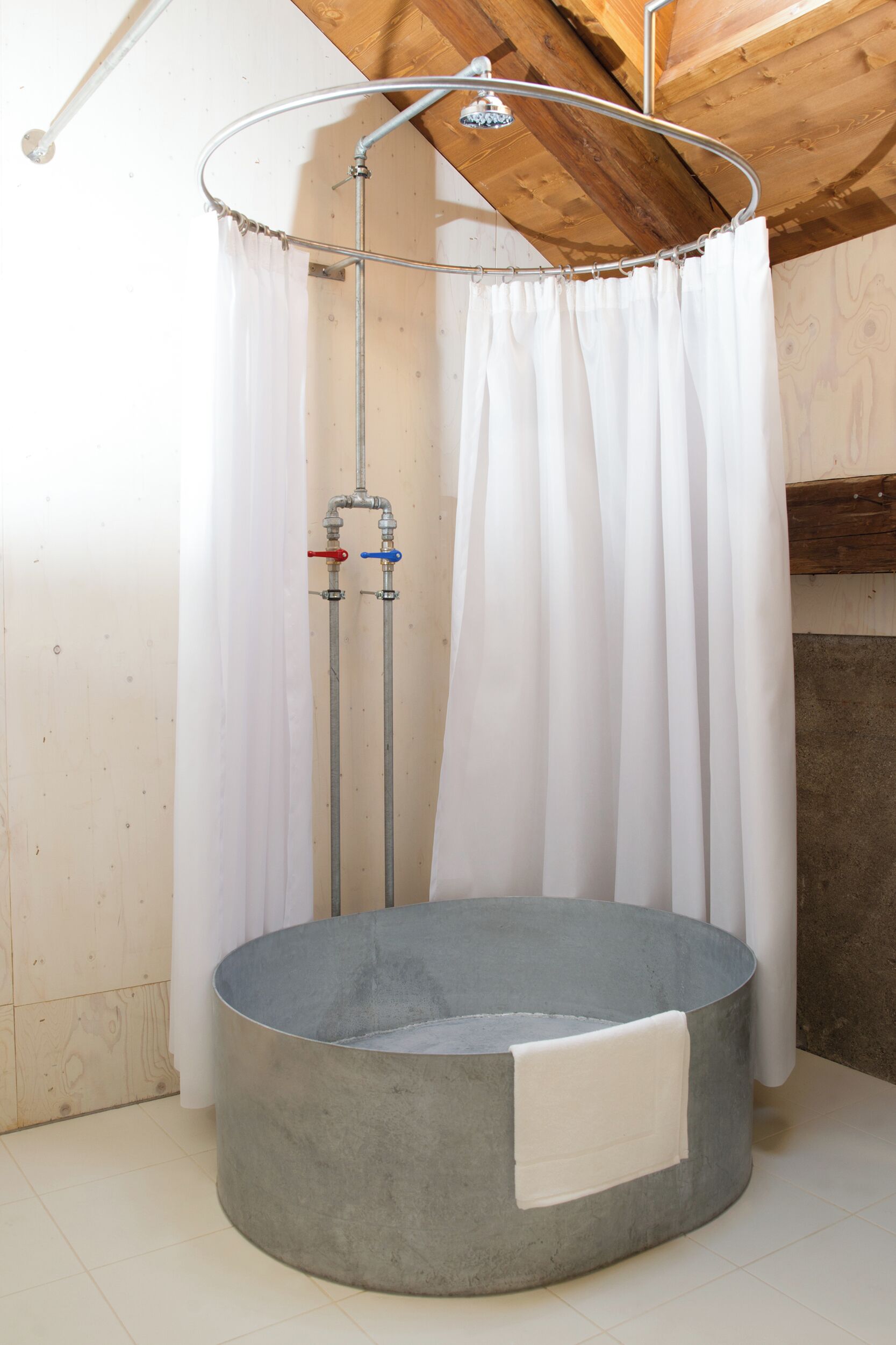 Un espacio de ducha con lavamanos circular, cabezal de ducha y cortina.