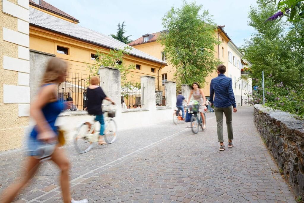 A cobblestone street with pedestrians and cyclists.