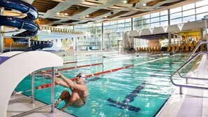 An indoor swimming pool with clear lanes, a diving board, and a large windowed area. - Alter Schlachthof (Bressanone)