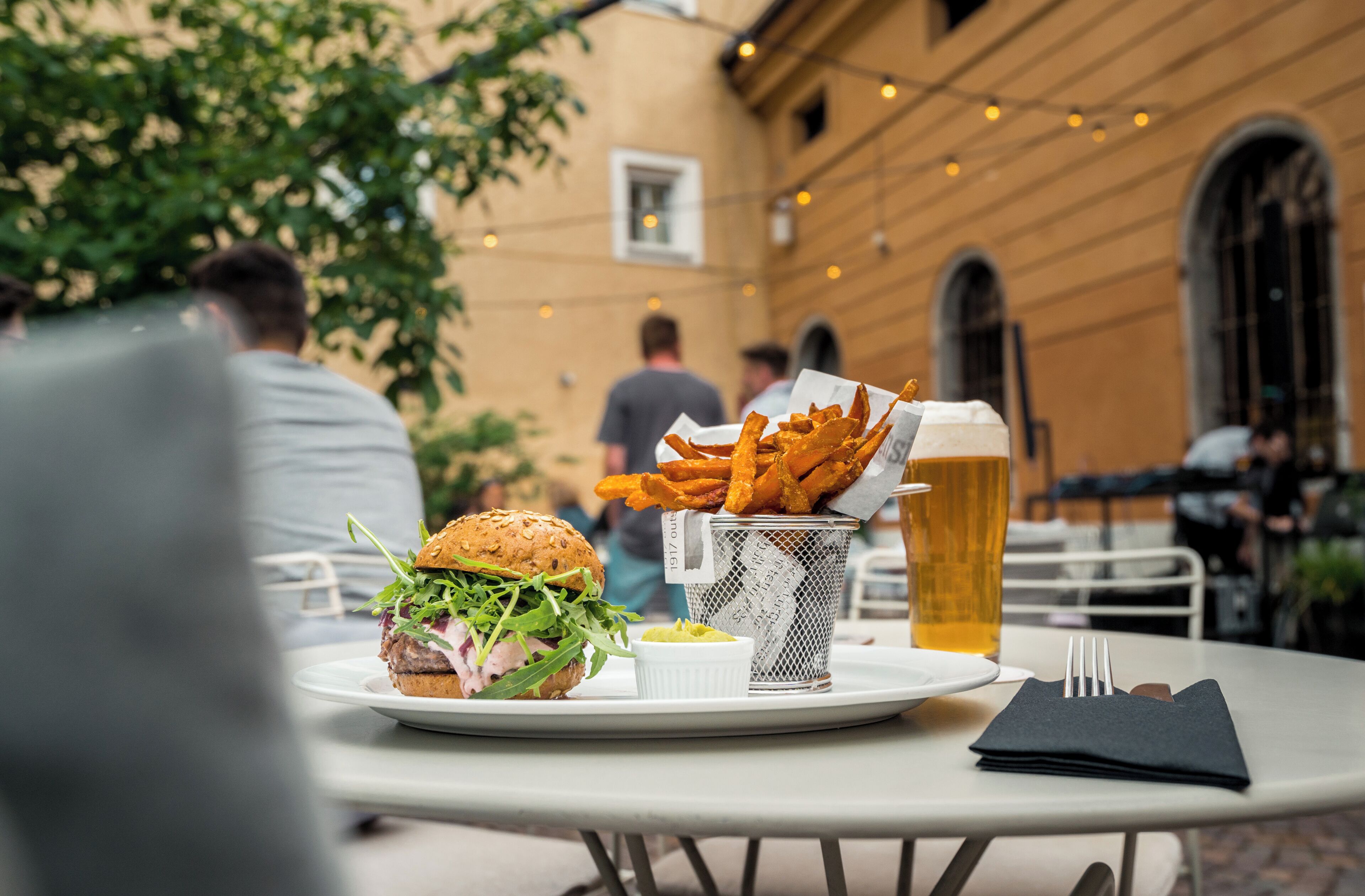 A table with a burger, fries, and a beer in a glass.