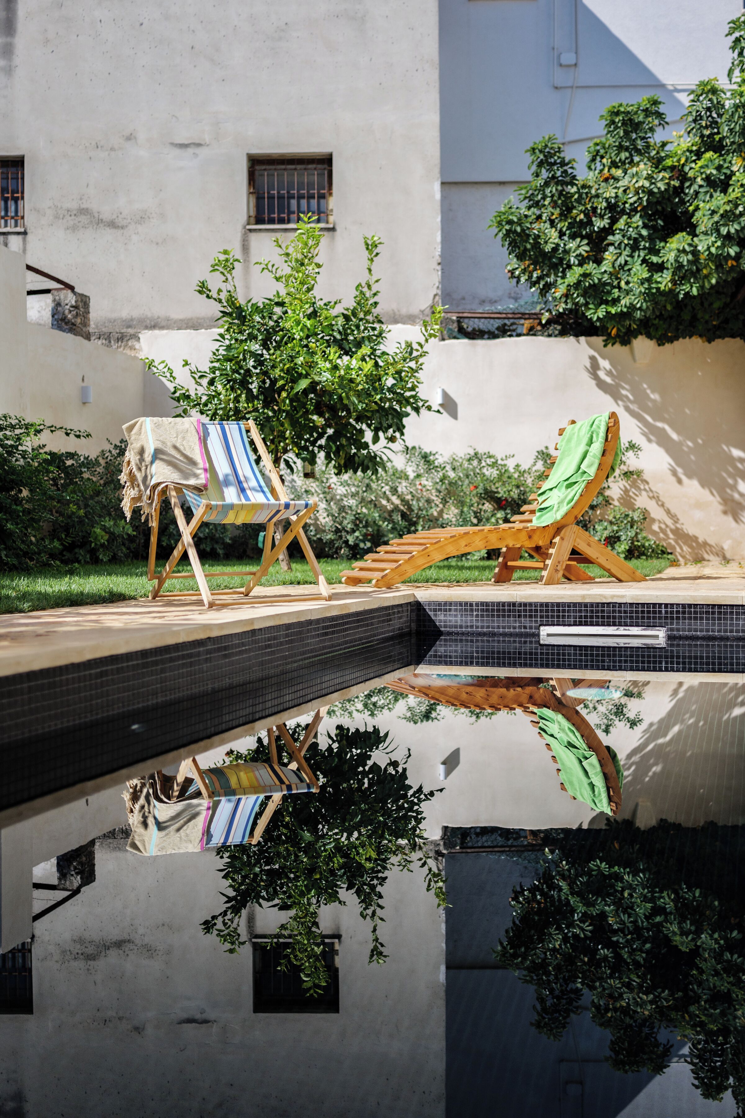 Un espace aménagé au bord de la piscine, avec des chaises longues et une piscine carrelée.